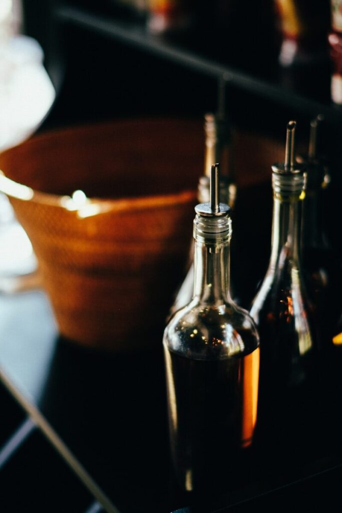 three bottles of olive oil and a bowl of olives