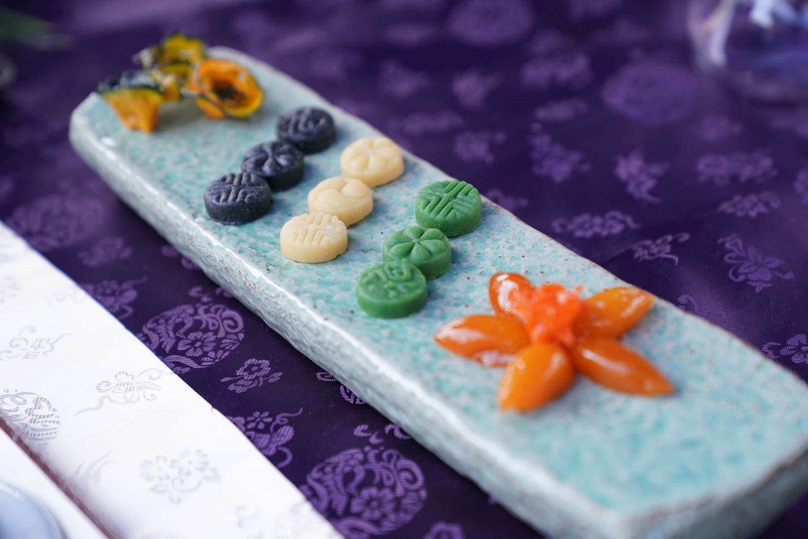 Artistic arrangement of traditional Korean sweets on a ceramic plate, with vibrant colors and intricate designs.