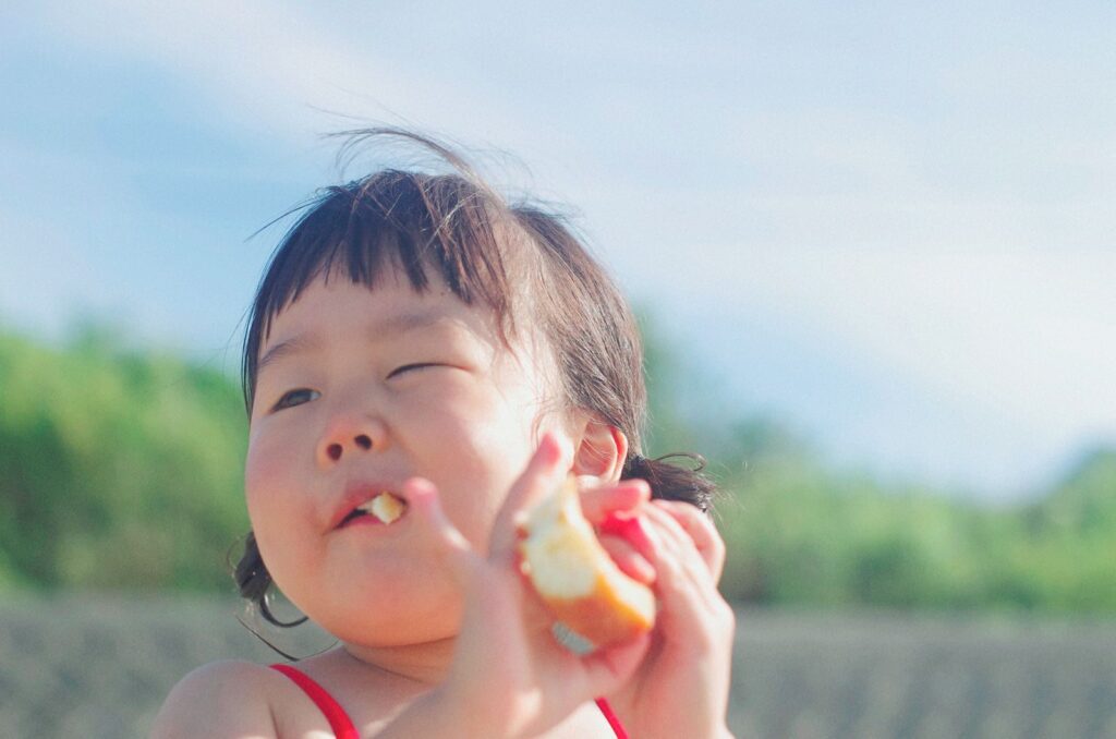 A joyful young child enjoying a snack outdoors during a sunny summer day, capturing innocence and happiness.