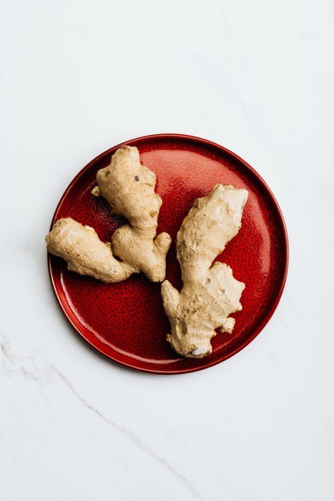Fresh ginger root on a vibrant red plate, perfect for healthy culinary use.
