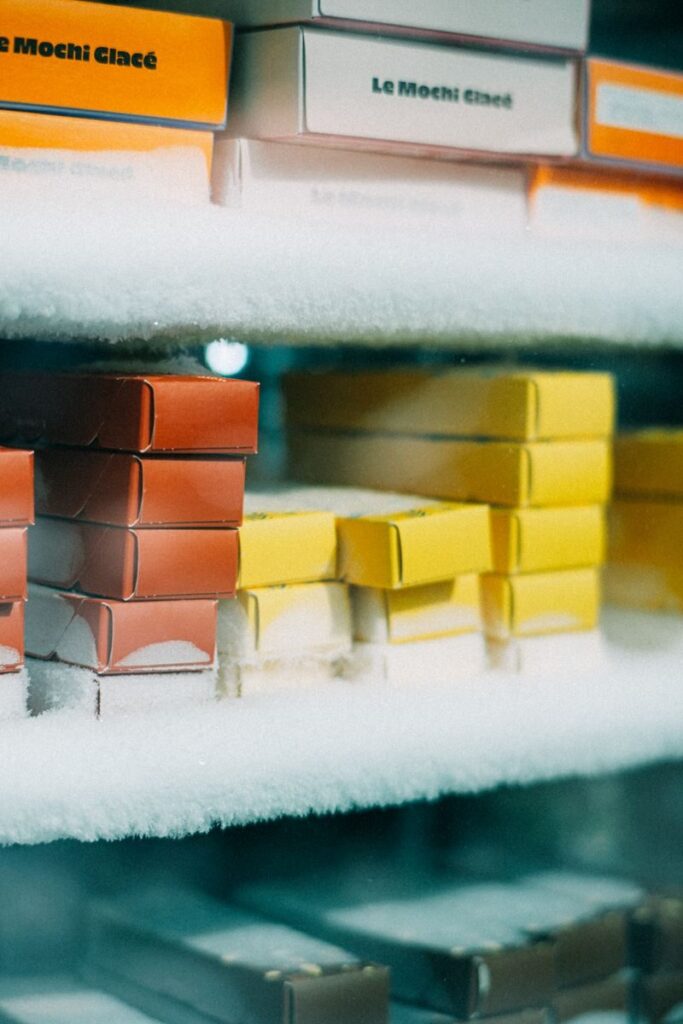 Stacked mochi ice cream boxes in a frost-covered display freezer.