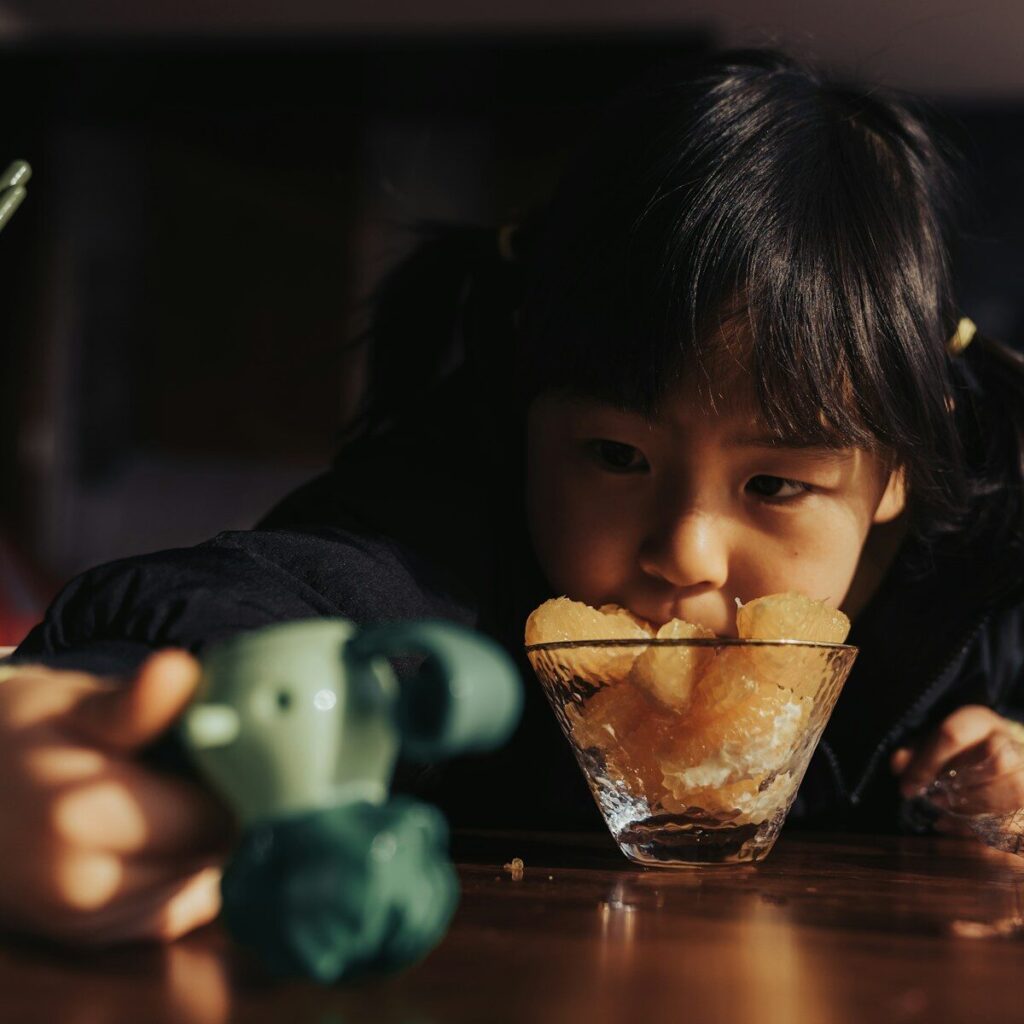 girl sipping from clear drinking glass
