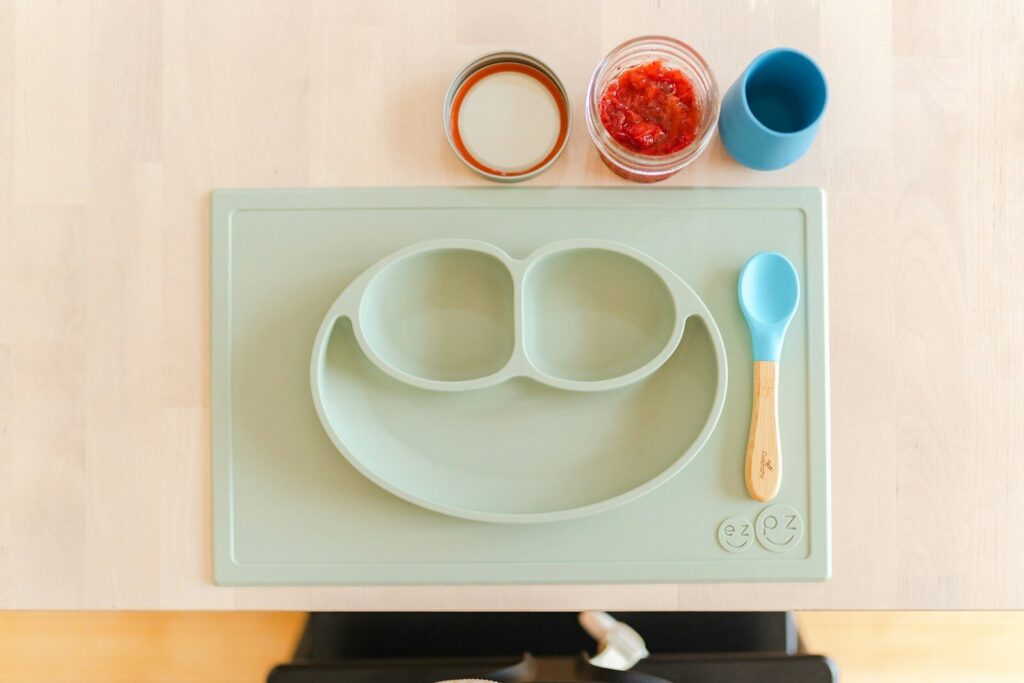 a child's plate with two spoons and a spoon rest on a stove
