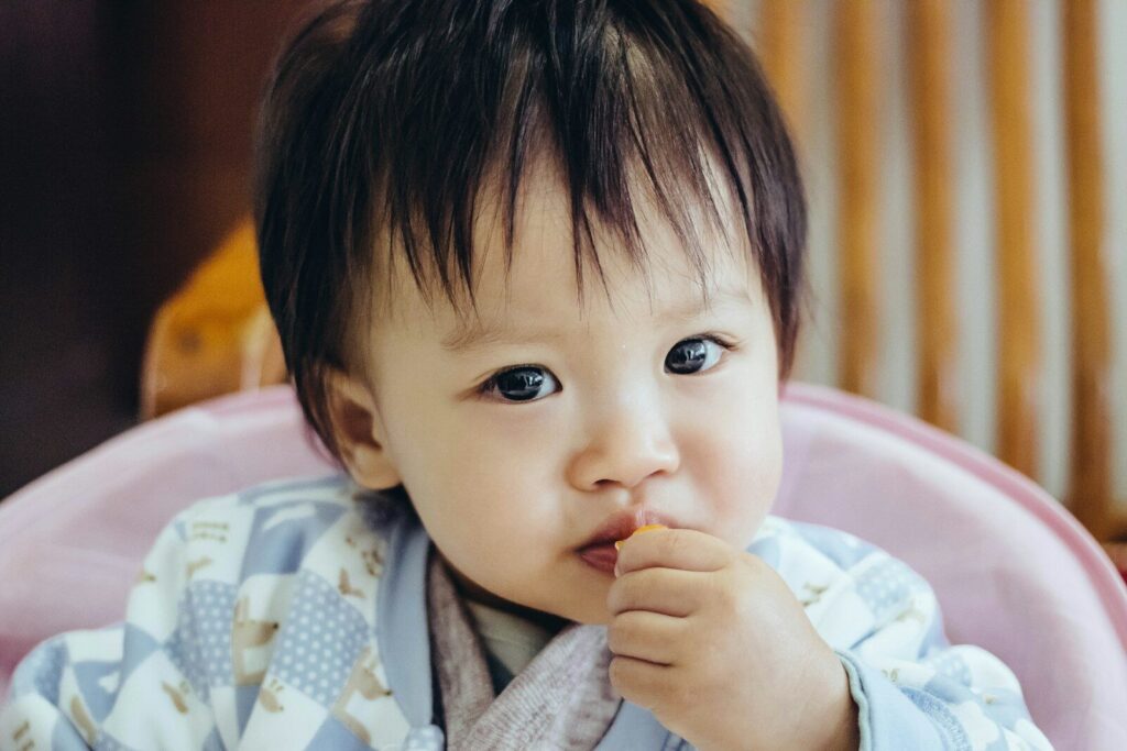 baby wearing blue pajama eating photograph