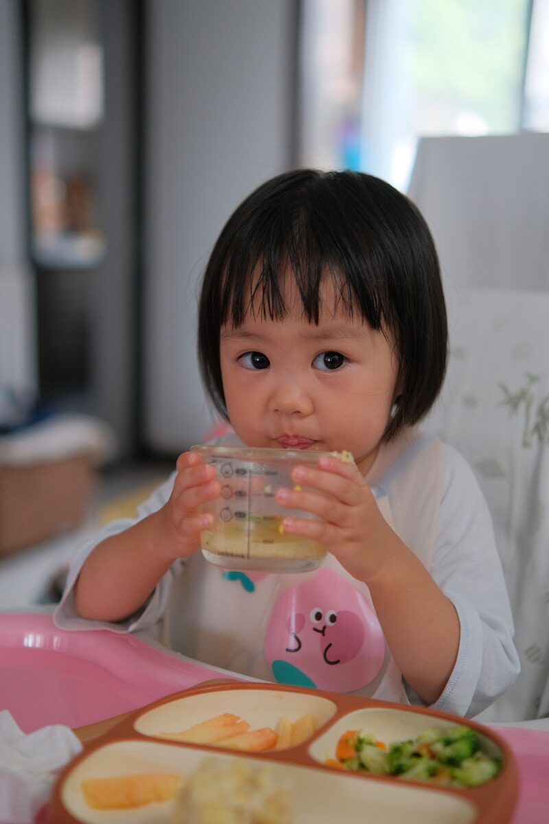 A little girl sitting at a table with a bowl of food