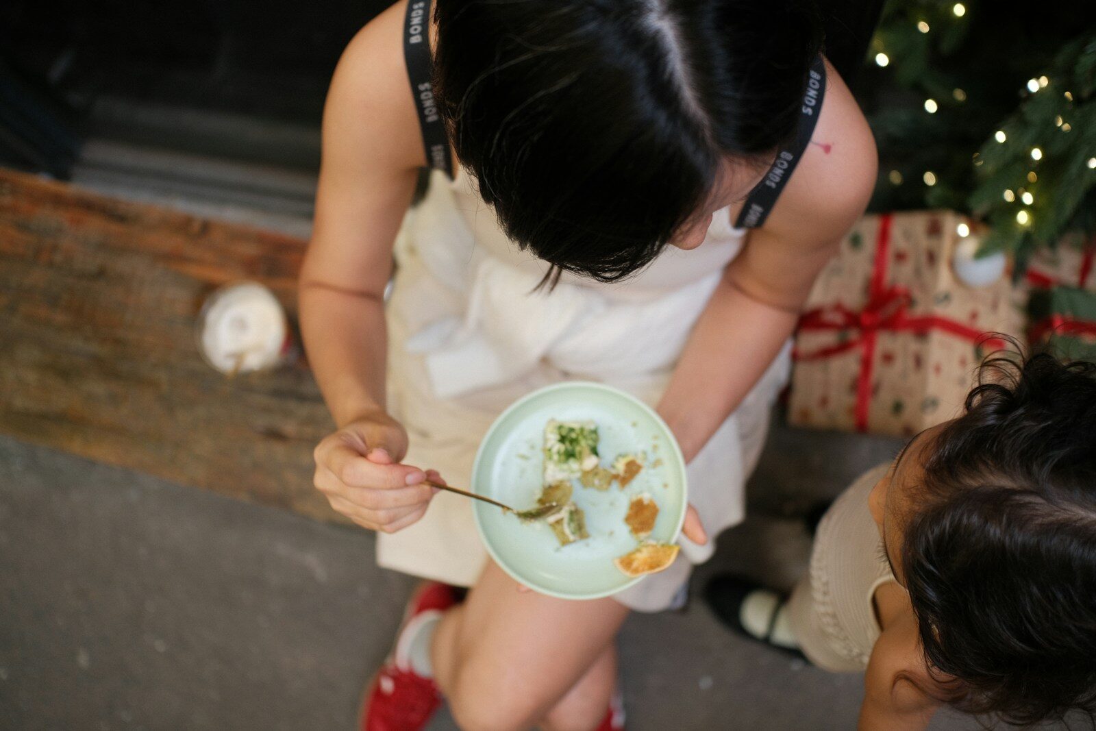 Woman eating food from plate with child nearby