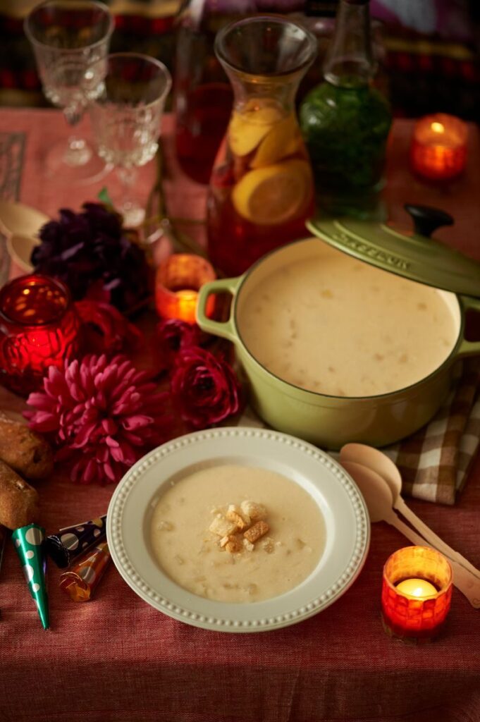 A warm, inviting dinner table setup with creamy soup, decorative candles, and flowers.