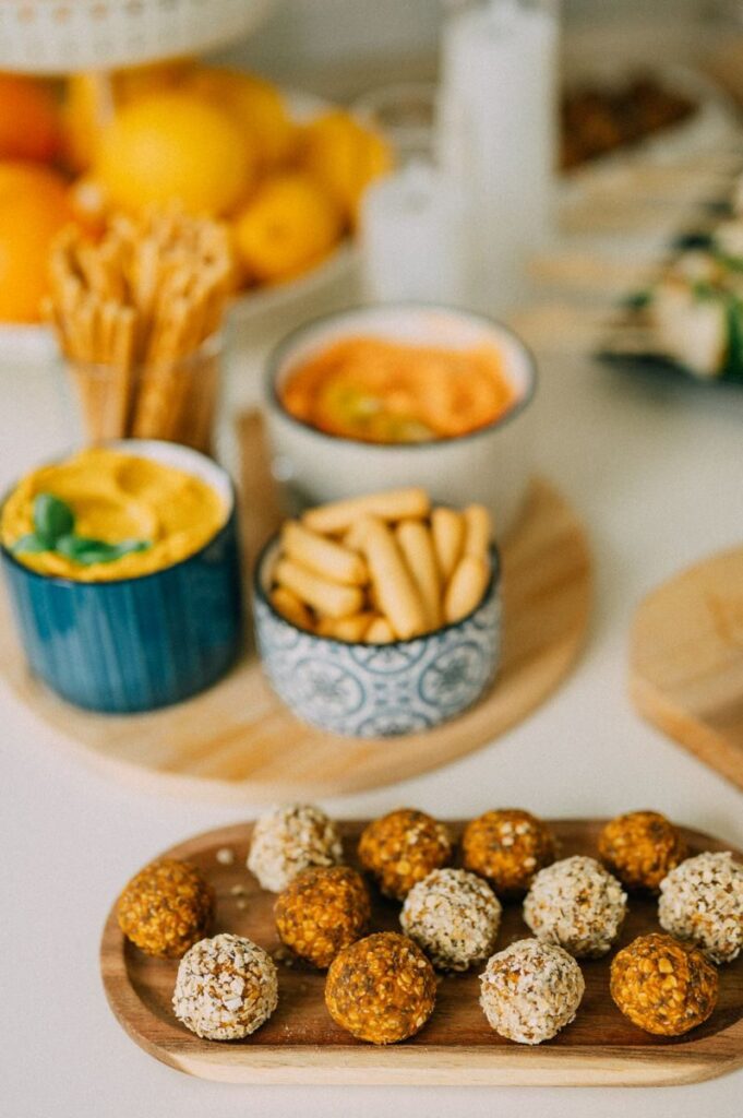 Close-up of various coated snacks on a tray surrounded by dips and fruits.