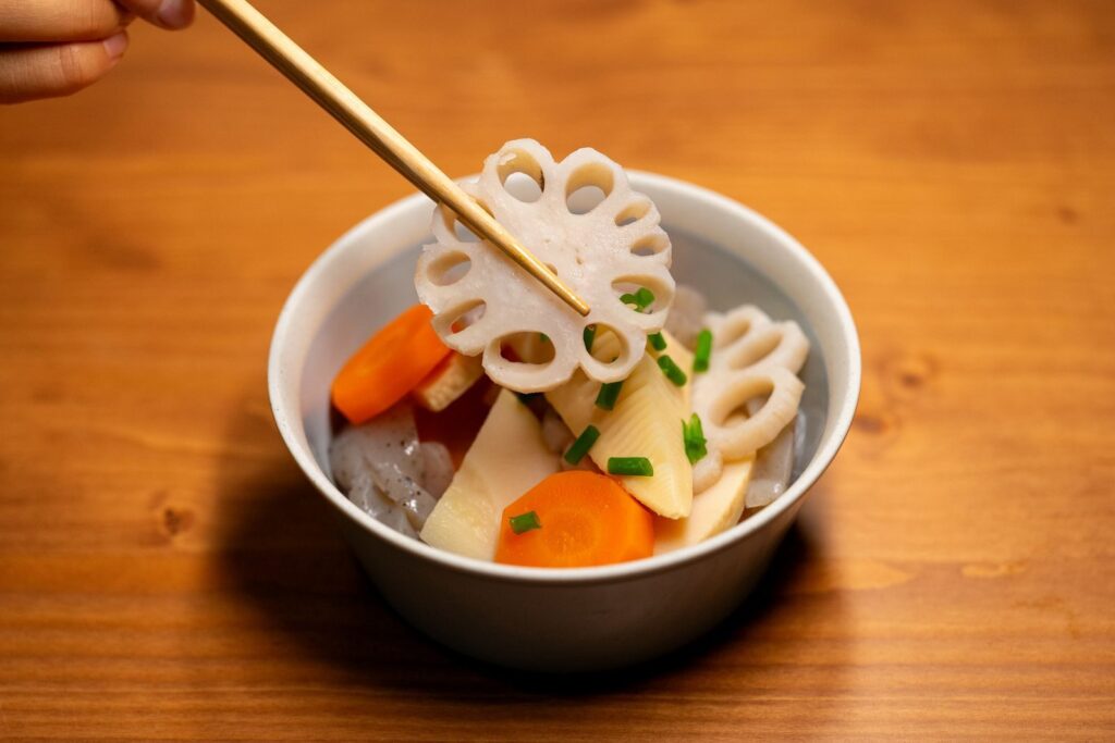 Appetizing dish of lotus root and vegetables served in a ceramic bowl, showcasing Asian culinary tradition.